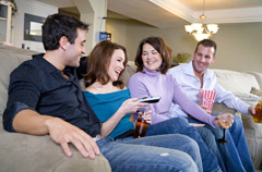 Four friends relaxing together on a couch with drinks and popcorn